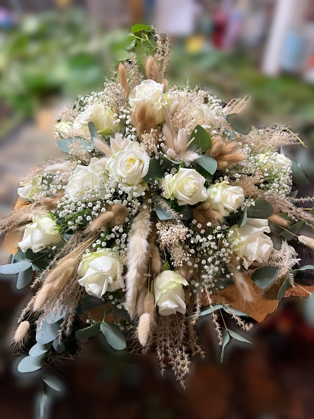 Gesteck aus weißen Rosen, Schleierkraut, Eukalyptus und Trockengräsern