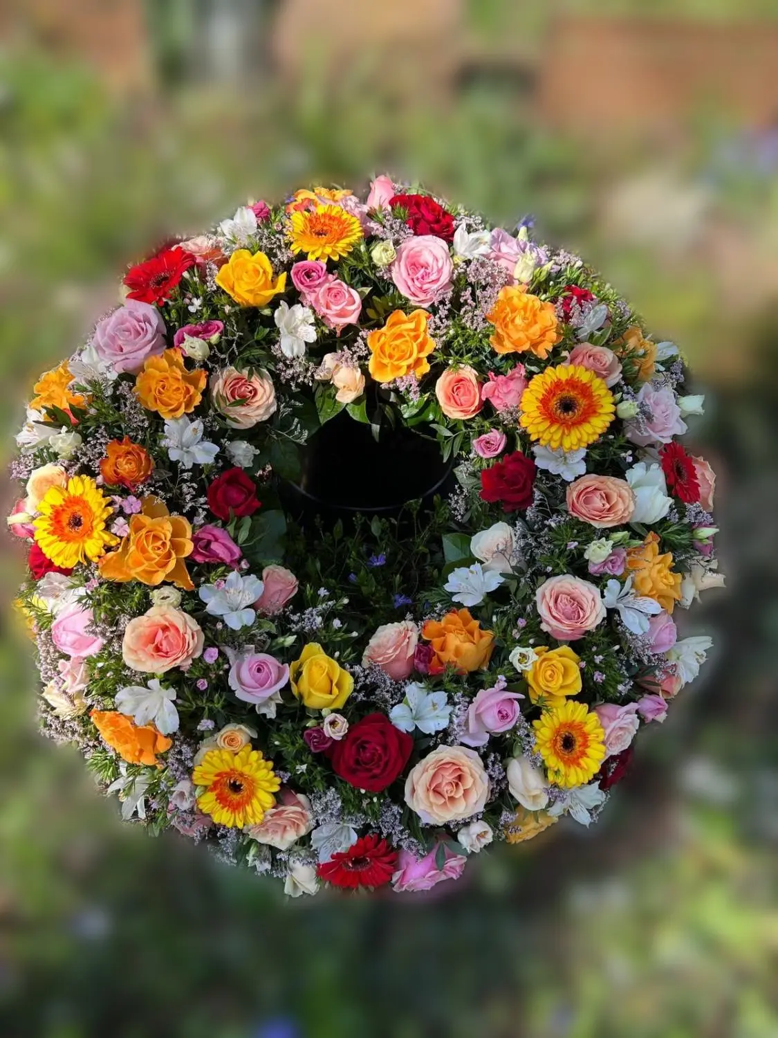 Bunter Kranz aus Rosen, Gerbera und Alstroemerien, am Grab abgelegt